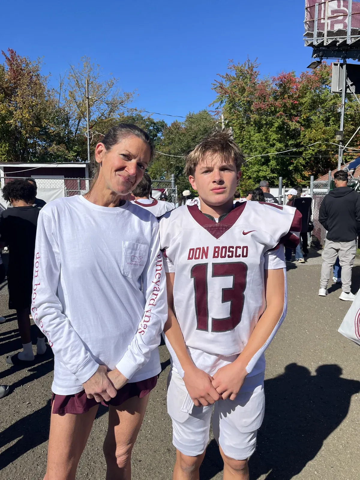 Two people posing beside a football field